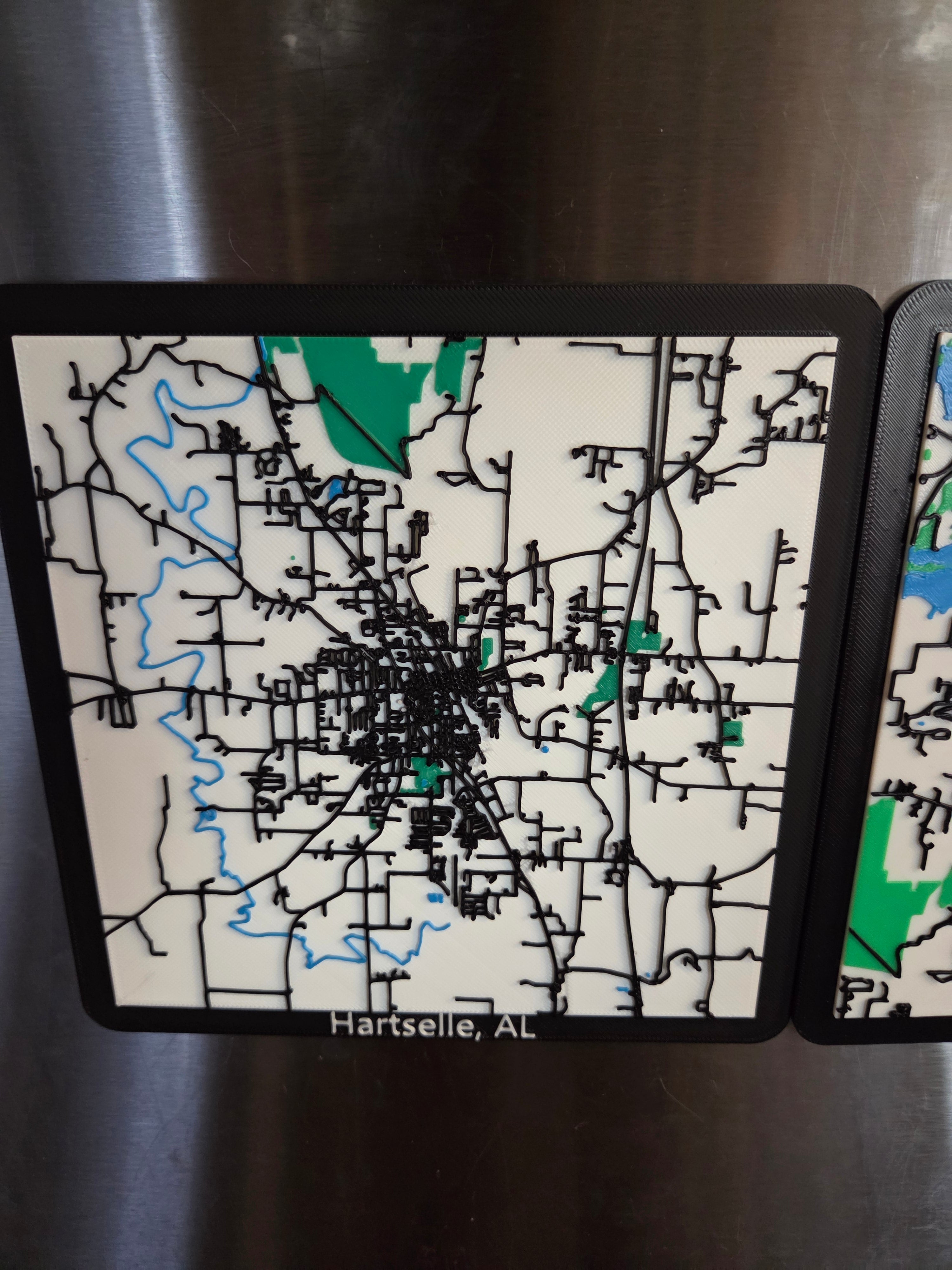 Map design on a metallic surface with 'Hartsselle, AL' text.
